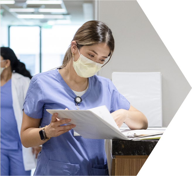 A female nurse reads papers in a binder